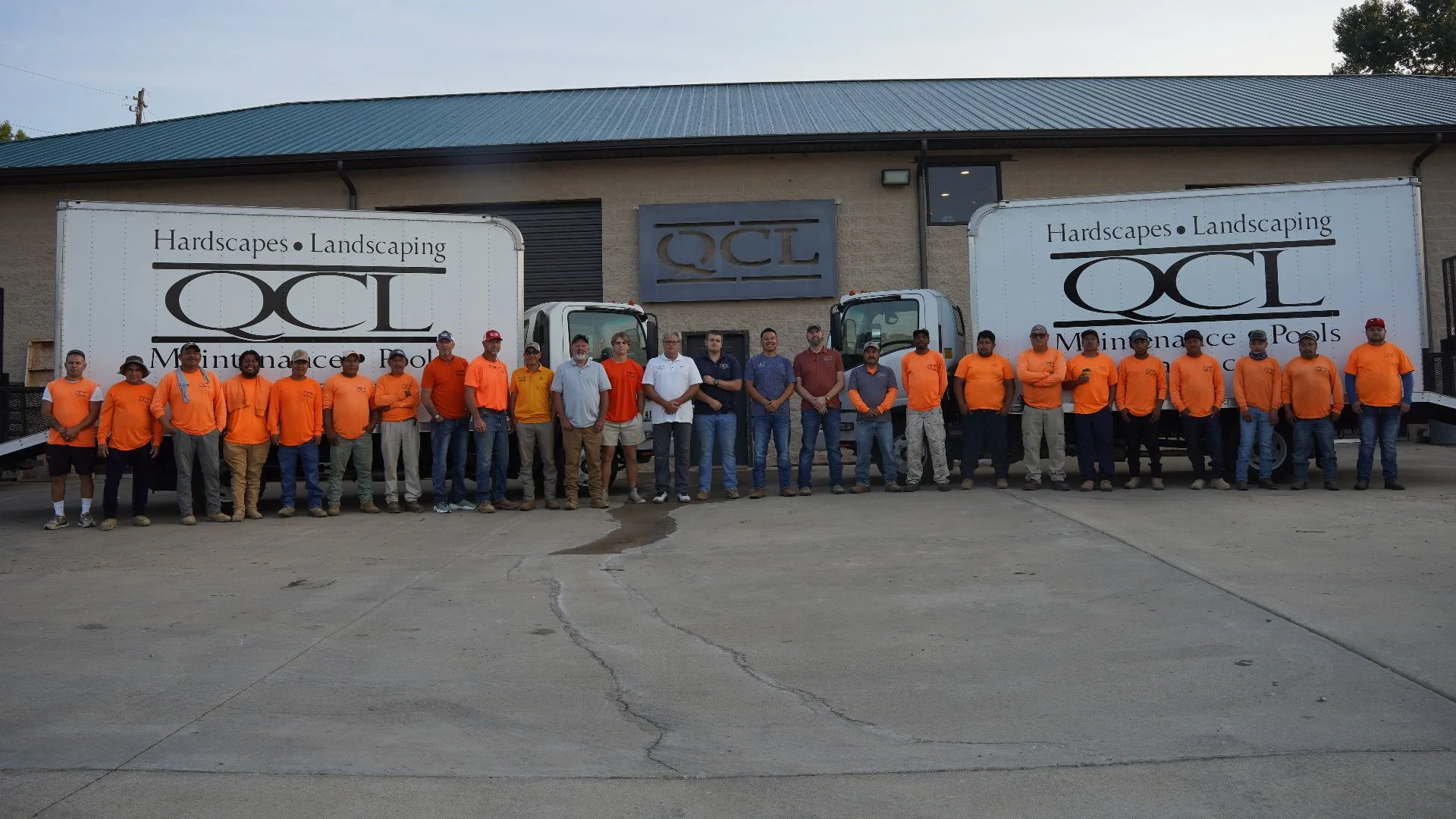 Landscape crew with orange shirts in front of white truck.