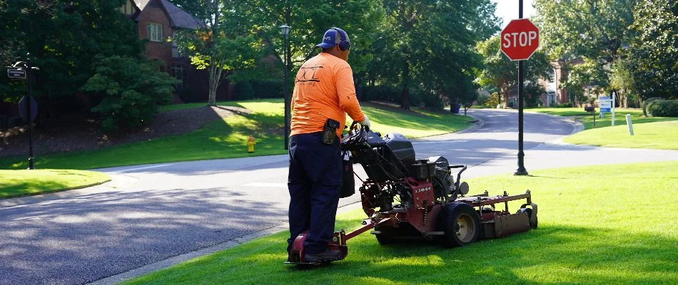 Crew mowing a lawn in New Market, AL, near the street.