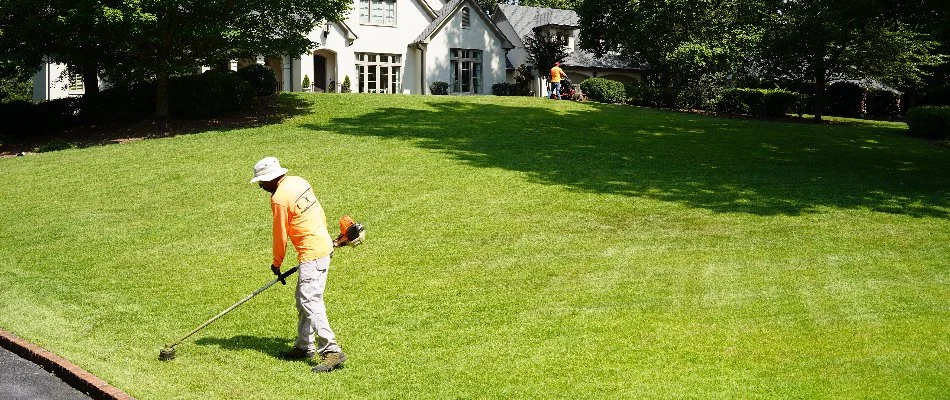 Crew string-trimming a lawn in Meridianville, AL.
