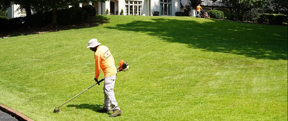 Crew string trimming grass in Greystone, AL, during a lawn mowing service.