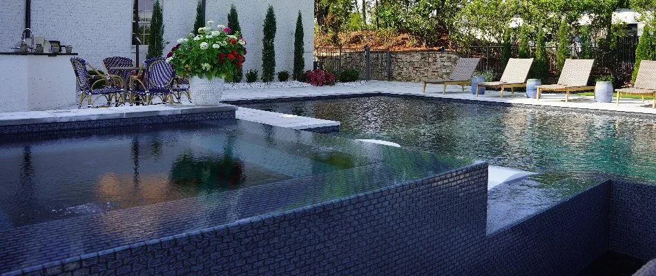 A swimming pool in Mountain Brook, AL, with a spa and seating.