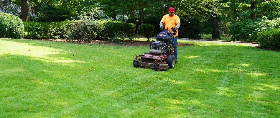 Worker in an orange shirt mowing a lawn in Mountain Brook, AL.