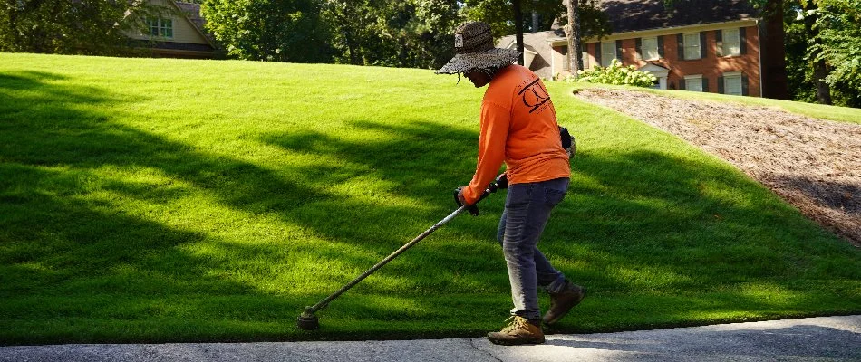 Worker string-trimming grass along a walkway in Mountain Brook, AL.