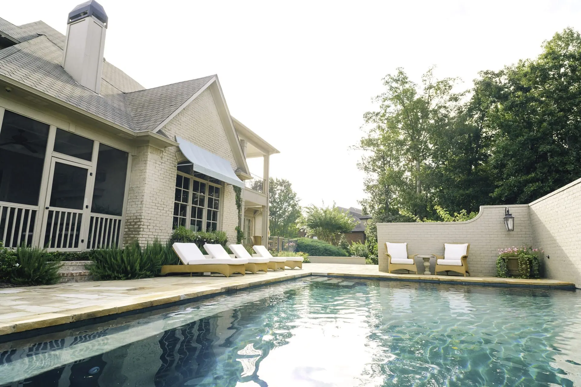 Pool with sun deck and chairs on paver patio at a home in Liberty Park, AL.