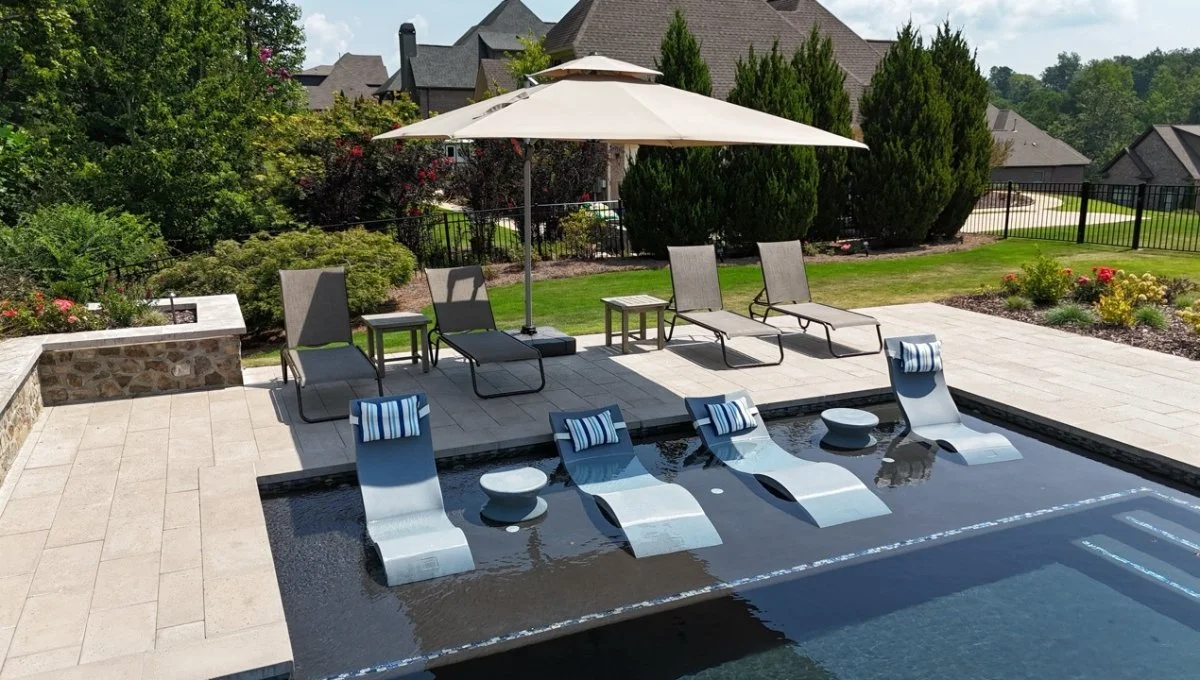 Pool with sun deck and chairs on paver patio at a home in Liberty Park, AL.